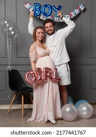 Full length view of a amused couple holding up inscription boy or girl during gender reveals party, over balloons. - Shutterstock ID 2177441767