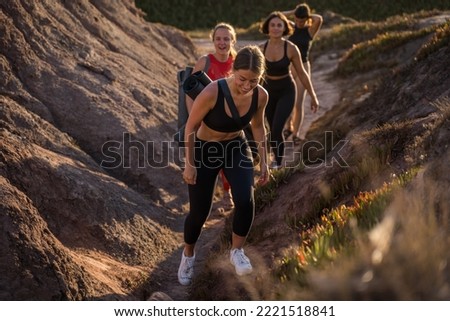 Full length view of the brunette women going through the grassy hill with yoga mats