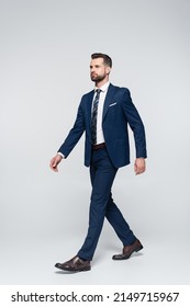 Full Length View Of Confident Businessman In Blue Suit Walking On Grey