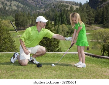 Full Length View Of Father And Giving Young Daughter Golf Lesson.