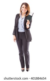 Full Length View Of A Female Sales Executive Of An Airline Holding A Boarding Pass And A Passport On A White Background