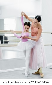 Full Length View Of Girl Training In Ballet School Near Young Dance Teacher