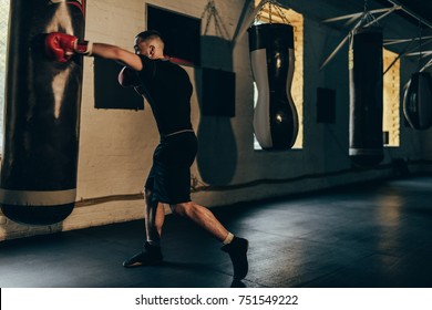 full length view of muscular young boxer training with punching bag - Powered by Shutterstock