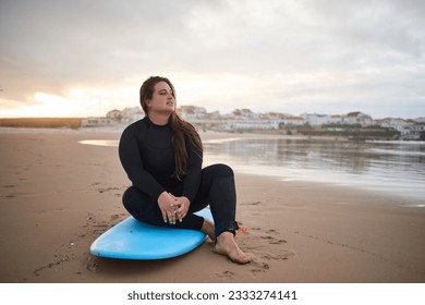 Full length view of the romantic overweight surfer woman looking at the ocean - Powered by Shutterstock