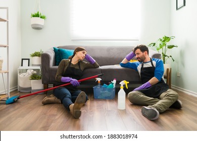 Full length view of a young couple sitting on the floor and looking tired of cleaning and doing chores at home - Powered by Shutterstock