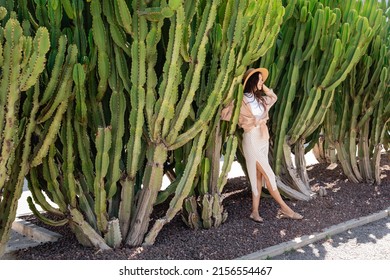 Full Length Of Woman In Straw Hat And Skirt Near Green Huge Cactuses