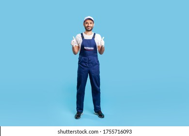 Full length workman in overalls, cap and protective gloves standing, showing thumbs up, like gesture and smiling, recommending good house repair services. studio shot isolated on blue background - Powered by Shutterstock