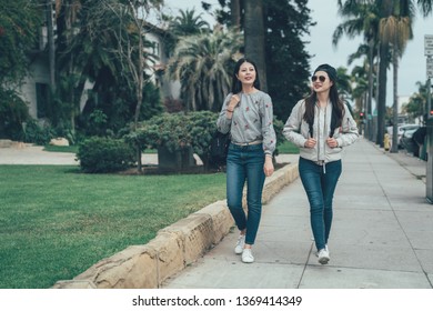 full length of young asian girl backpackers walking on street outdoor by trees along road in Santa Barbara County Courthouse. two beautiful college students after school talking back to home. - Powered by Shutterstock