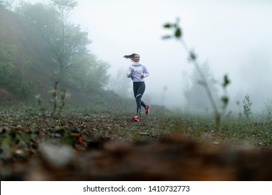 Full length of young athletic woman running in nature on misty morning. Copy space.  - Powered by Shutterstock