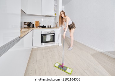 Full Length Of Young Attractive Woman Housewife Cleaning Modern Apartment, Washing Mopping Kitchen Floor With Damp Mop And Detergent, Female Doing Household Chores. Housework And Housekeeping