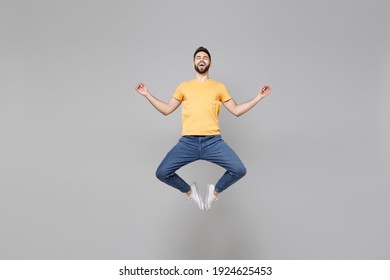 Full length of young bearded man 20s wearing yellow basic t-shirt jump high hold hands in yoga gesture, relaxing meditating, trying to calm down levitating isolated on grey background studio portrait. - Shutterstock ID 1924625453