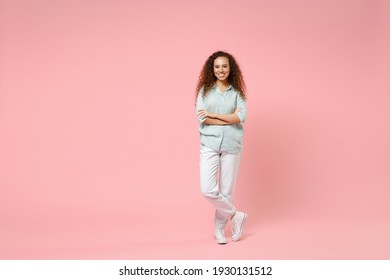 Full Length Young Black African American Happy Smiling Positive Curly Woman 20s Wearing Blue Casual Shirt Looking Camera Hold Hands Crossed Folded Isolated On Pastel Pink Background Studio Portrait