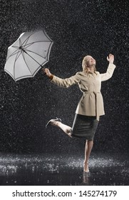 Full length of a young businesswoman in overcoat with umbrella enjoying the rain