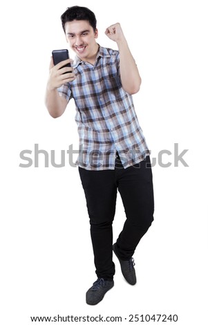 Full length of young casual man expressing happiness after read good news on his smartphone