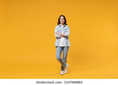 Full Length Of Young Caucasian Smiling Happy Confident European Cute Woman 20s Wearing Stylish Casual Denim Shirt White T-shirt Hold Hands Crossed Folded Isolated On Yellow Background Studio Portrait.