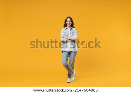 Full length of young caucasian smiling happy confident european cute woman 20s wearing stylish casual denim shirt white t-shirt hold hands crossed folded isolated on yellow background studio portrait.