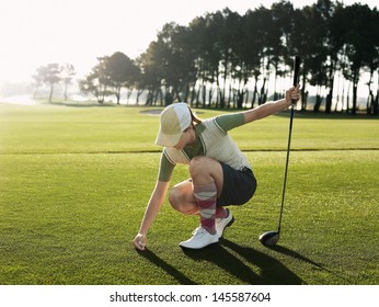 Full length of young female golfer placing ball on tee - Powered by Shutterstock