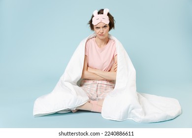 Full length young frowning woman in pajamas jam sleep eye mask rest at home sit wrap covered blanket duvet hold hands crossed folded isolated on pastel blue background Bad mood night bedtime concept - Shutterstock ID 2240886611