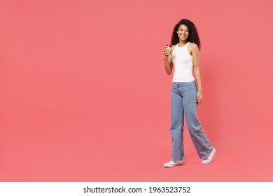 Full Length Young Fun Satisfied Excited Happy Student African American Woman 20s In Casual White Tank Shirt Holding Paper Cup Of Coffee Sniff Walk Go Isolated On Pink Color Background Studio Portrait