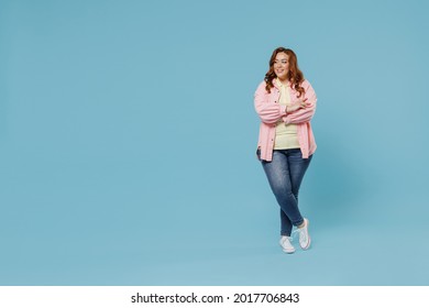 Full Length Young Fun Smiling Redhead Chubby Overweight Woman 30s Wearing In Pink Shirt Jeans Casual Clothes Hold Hands Crossed Folded Look Aside Isolated On Pastel Blue Background Studio Portrait.