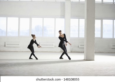 Full length of young girl learning ballet from her instructor in empty warehouse - Powered by Shutterstock