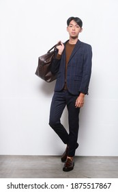 full length young handsome businessman 
 man wearing striped suit with sweater and pants holding handbag on gray background
 - Shutterstock ID 1875517867