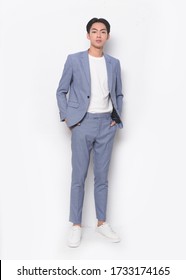 full length young handsome man wearing in blue suit with t-shirt and pants , sneakers standing hands holds pockets