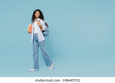 Full length young happy african american girl teen student wear denim clothes backpack hold book walk go isolated on blue background studio portrait Education in high school university college concept - Powered by Shutterstock