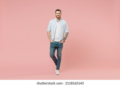 Full length young happy cheerful friendly caucasian unshaven man 20s in blue striped shirt white t-shirt look camera isolated on pastel pink color background studio portrait. People lifestyle concept