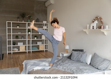 Full Length Young Hispanic Happy Woman In Pyjama Feels Untroubled Dancing On Bed In Bedroom Alone At Home. Celebrate Carefree Day Off, Long Awaited Holidays, Enjoy Life New Day At Modern Own Apartment