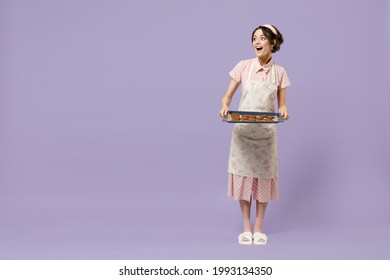 Full Length Young Housewife Housekeeper Chef Cook Baker Woman Wearing Pink Apron Show Chocolate Cookies Biscuits On Baking Sheet Look Aside Isolated On Pastel Violet Background Cooking Food Concept