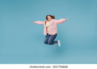 Full Length Young Joyful Overjoyed Smiling Redhead Chubby Overweight Woman 30s Wearing In Pink Shirt Jeans Jumping High With Oustretched Hands Flying Have Fun Isolated On Pastel Blue Background Studio