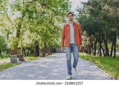 Full length young man 20s he wearing orange jacket blue t-shirt walking look camera rest relax in spring green city park go down alley sunshine lawn outdoors on nature. Urban lifestyle leisure concept - Shutterstock ID 2168812257