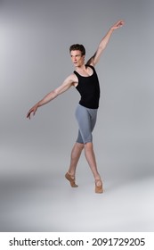 Full Length Of Young Man In Ballet Shoes Performing Ballet Dance On Grey