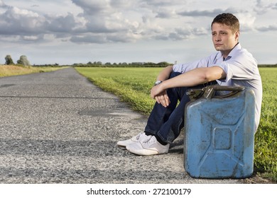 Full Length Of Young Man With Empty Gas Can Sitting By Road