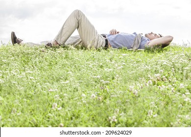Full length of young man lying on grass against sky