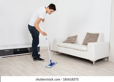 Full Length Of Young Man Mopping Floor At Home