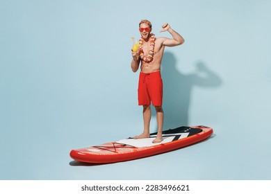Full length young man in red shorts swimsuit hawaii lei glasses stand sup board hold alcohol cocktail point thumb finger on himself isolated on blue background Summer vacation sea rest sun tan concept - Powered by Shutterstock