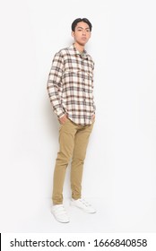 Full Length Young Man Wearing Plaid Shirt With Khaki Pants With Sneakers Posing In Studio


