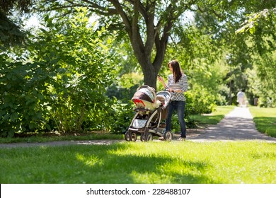 Full Length Of Young Mother Pushing Baby Carriage In Park