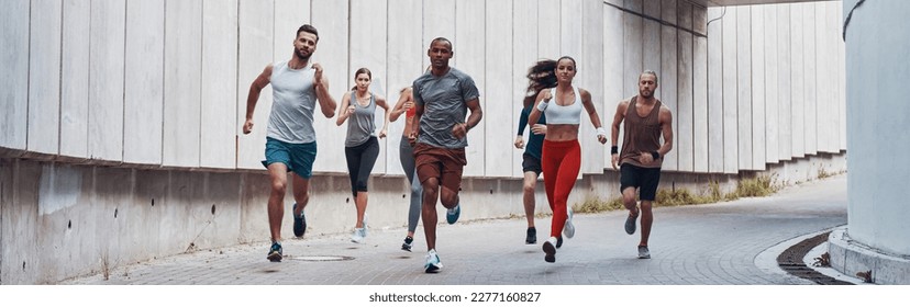 Full length of young people in sports clothing jogging outdoors together - Powered by Shutterstock