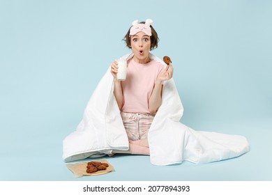 Full Length Young Shocked Woman 20s In Pajamas Jam Sleep Eye Mask Rest At Home Wrap Cover Blanket Duvet Sit Cookie Milk Eat Drink Isolated On Pastel Blue Background Studio Good Mood Breakfast Concept