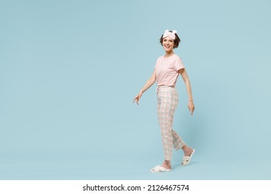 Full Length Young Smiling Caucasian Woman 20s Wearing Pajamas Jam Sleep Eye Mask Rest Relaxing At Home Walking Going Isolated On Pastel Blue Color Background Studio. Good Mood Night Bedtime Concept