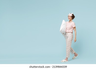 Full Length Young Smiling Caucasian Woman In Pajamas Jam Sleep Eye Mask Rest Relax At Home Holding Pillow Walking Going Isolated On Pastel Blue Color Background Studio. Good Mood Night Bedtime Concept