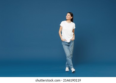 Full Length Of Young Smiling Confident Nice Attractive Beautiful Latin Woman 20s Wearing White Casual Basic T-shirt Keep Hands In Pockets Look Aside Isolated On Dark Blue Background Studio Portrait