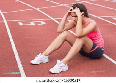 Full length of a young sporty woman sitting on the running track - Powered by Shutterstock