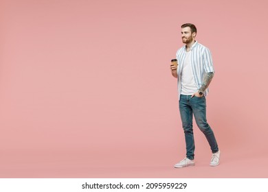 Full length of young unshaven man 20s wearing blue striped shirt hold takeaway delivery craft paper brown cup coffee to go walk isolated on pastel pink background studio portrait. Tattoo translate fun - Powered by Shutterstock