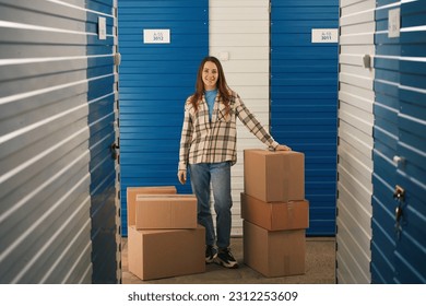Full length of young woman with big cardboard boxes in self storage unit - Shutterstock ID 2312253609