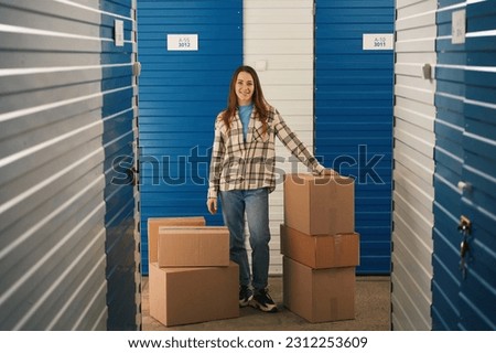 Full length of young woman with big cardboard boxes in self storage unit