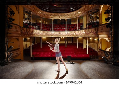 Full length of a young woman with script rehearsing on stage